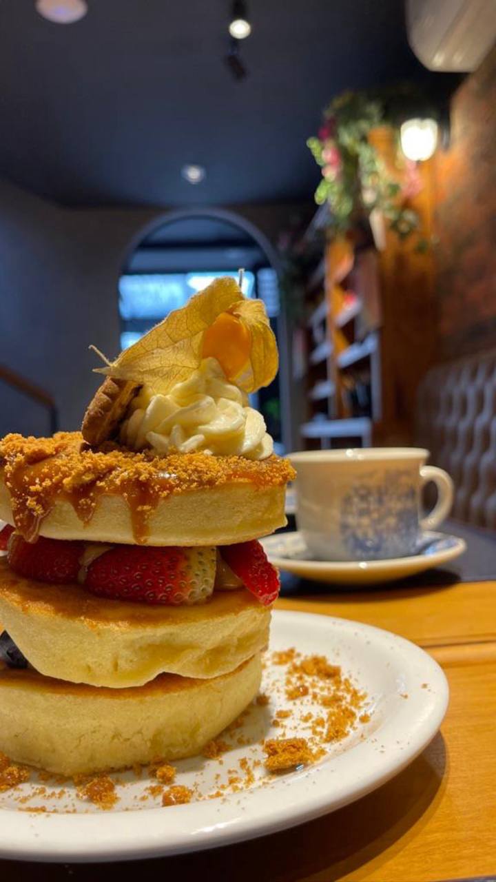 Sobremesa gourmet com bolo, calda dourada, morangos frescos e xícara de café em ambiente acolhedor